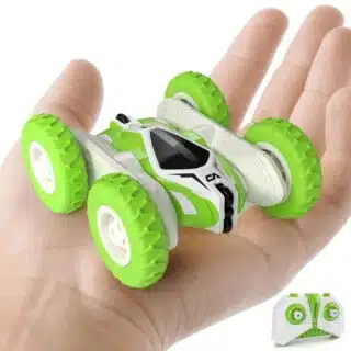 Photo d'une mini voiture cascadeuse verte tenue dans une main avec sa télécommande à coté.